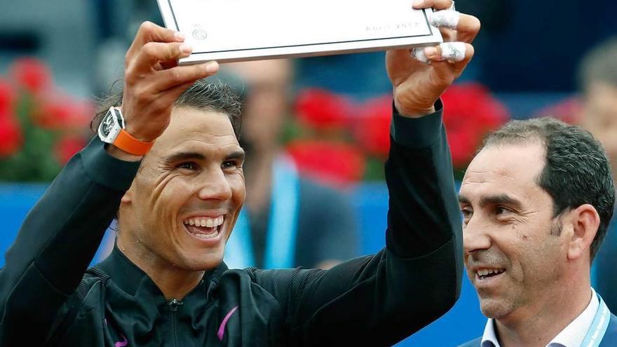 Rafa Nadal muestra la placa de la pista con su nombre junto a Albert Costa, director del torneo.