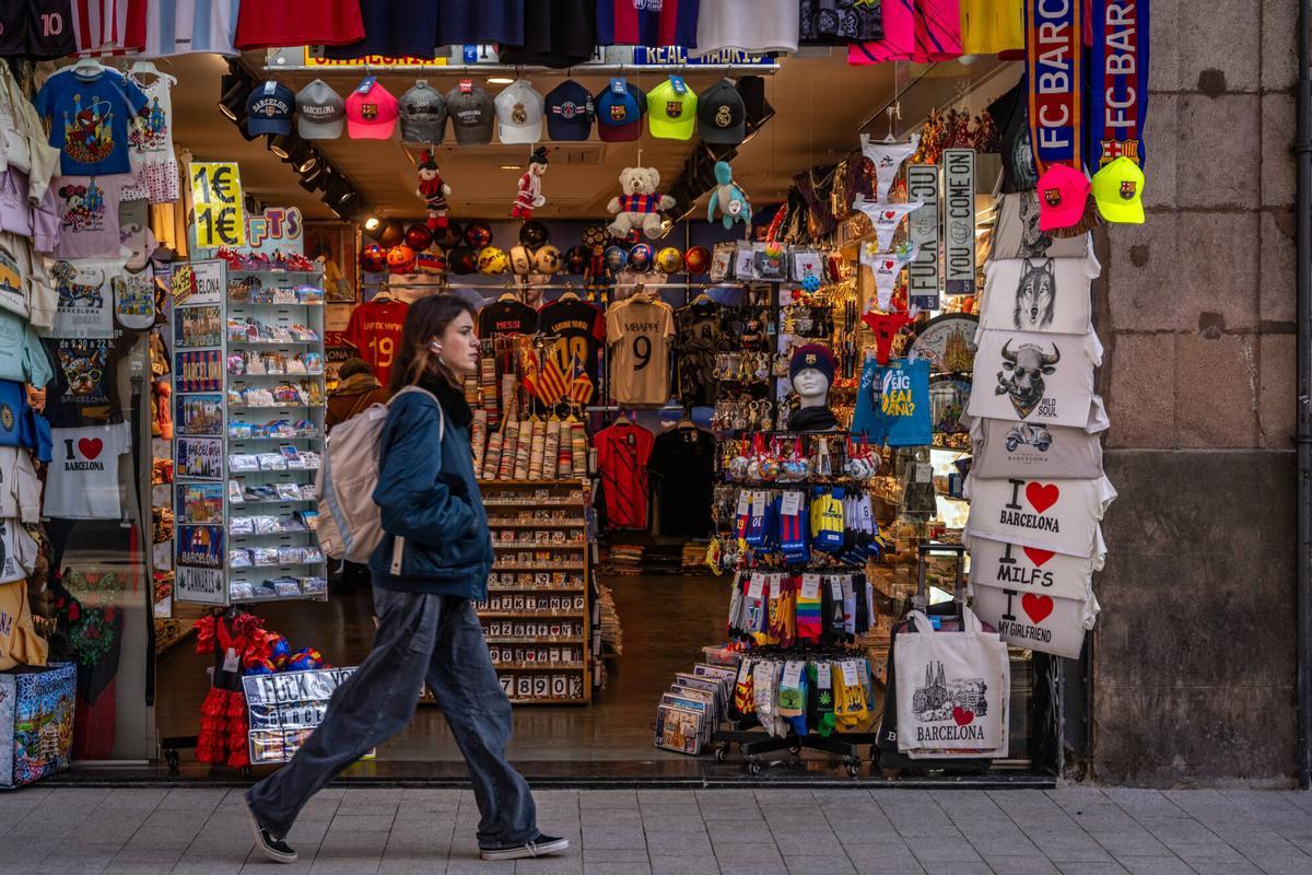 Una joven camina ante una tienda de suvenirs en Ciutat Vella, en Barcelona.