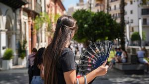 Se espera una jornada de calor intenso, con temperaturas que podrían llegar a los 40 grados. En la imagen, una mujer se abanica en una calle de Sevilla.