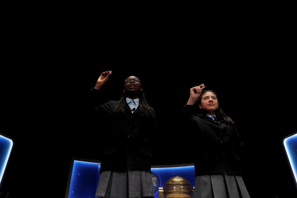 Las niñas del colegio de San ildefonso Yanisse Alexandra Soto (d) y Elisabeth Obarisiagbon Iyamu muestran las bolas con el número 69.823 que ha sido agraciado con uno de los quintos premios.