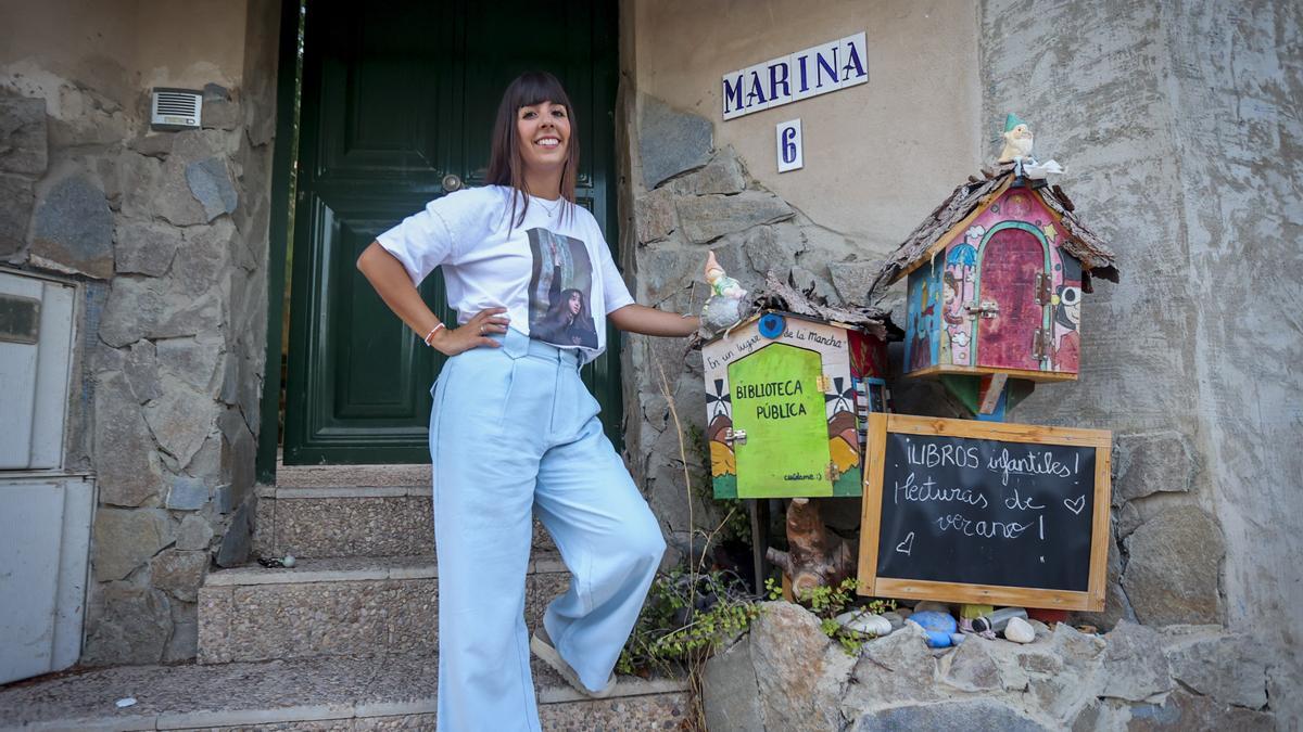 La escritora Marina Pérez junto a la biblioteca infantil que ha instalado en la puerta de su casa