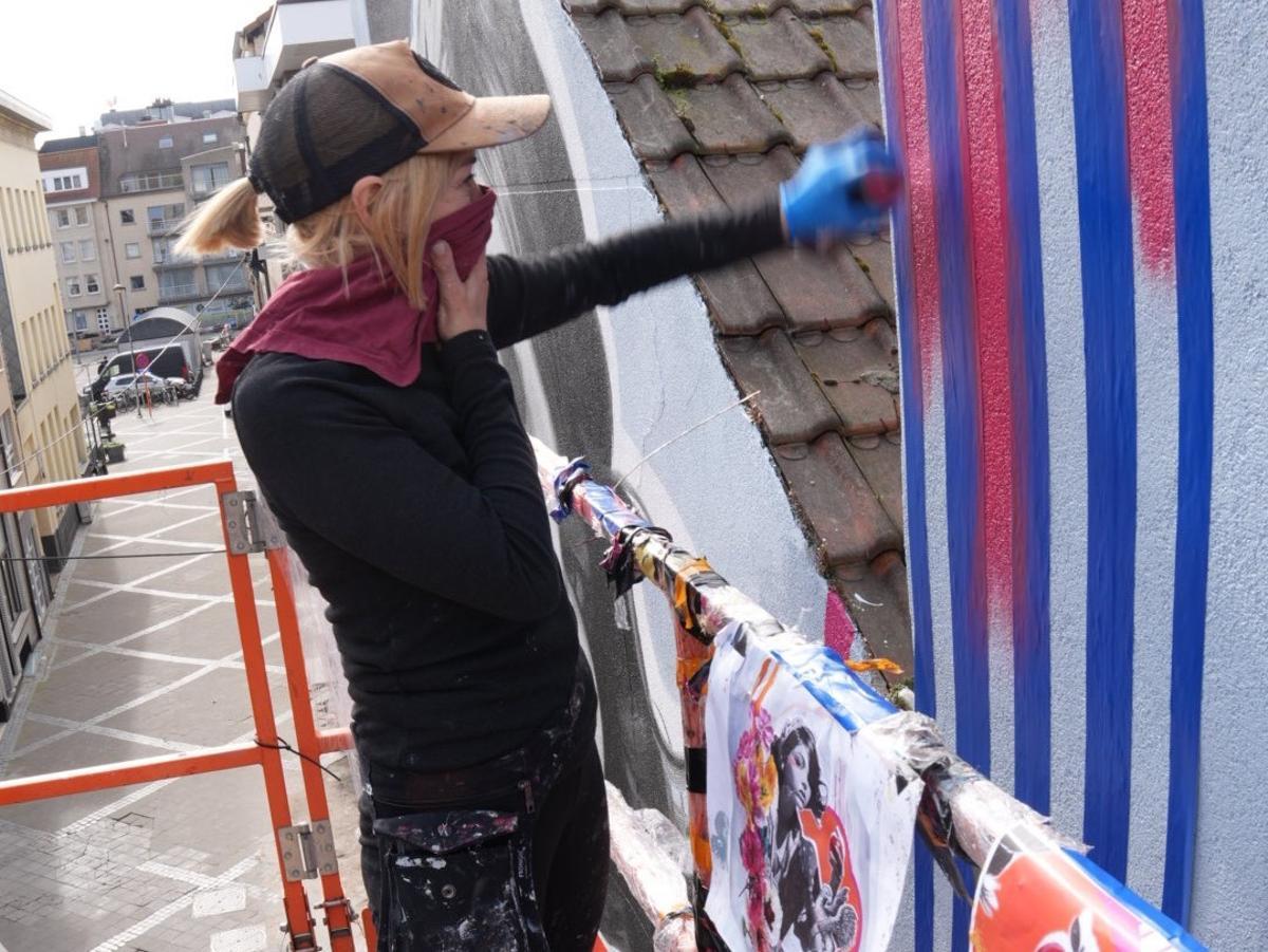 Imagen de la artista Lula Goce pintando un mural.