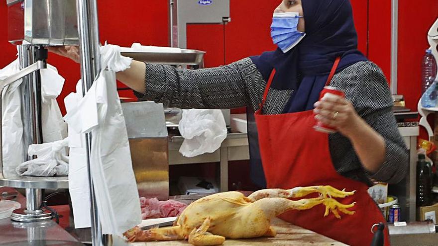 Asmaa prepara un pollo en la carnicería ‘halal’ . |   // RICARDO GROBAS