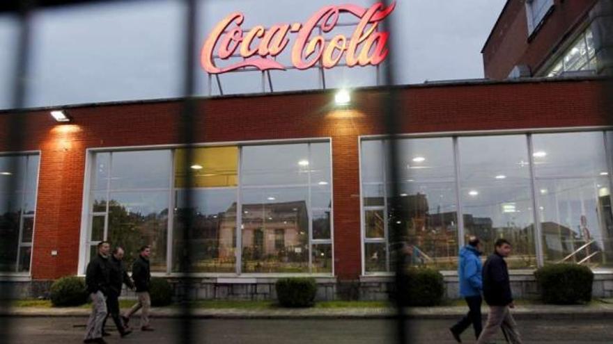 Trabajadores pasan por delante de una fábrica española de Coca-Cola. / luisma murias