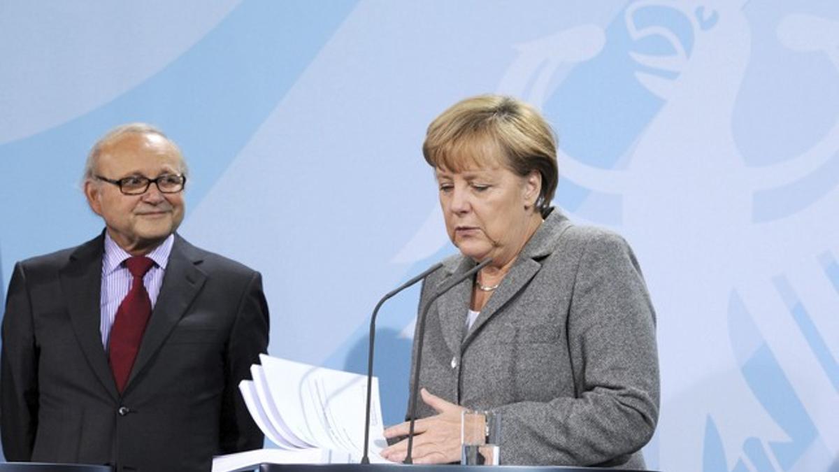 La cancillera alemana, Angela Merkel, repasa el informe anual del Consejo Asesor de Economistas del Gobierno alemán, junto al presidente del grupo, Wolfgang Franz, el miércoles en Berlín.