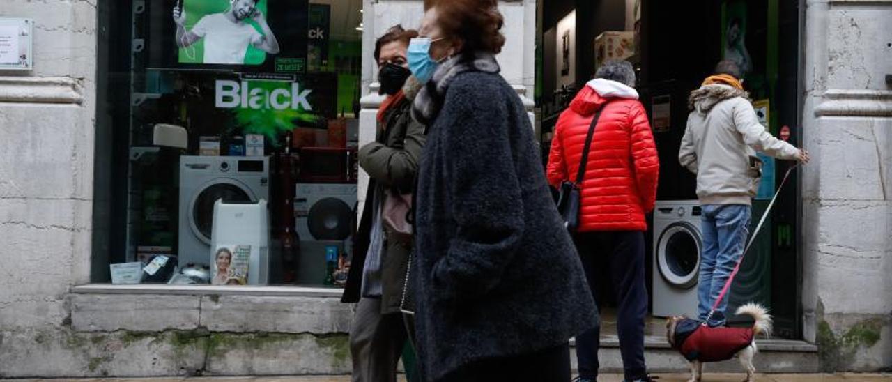 Viandantes frente a una tienda de Avilés que ya anuncia las rebajas del &quot;Black friday&quot;.