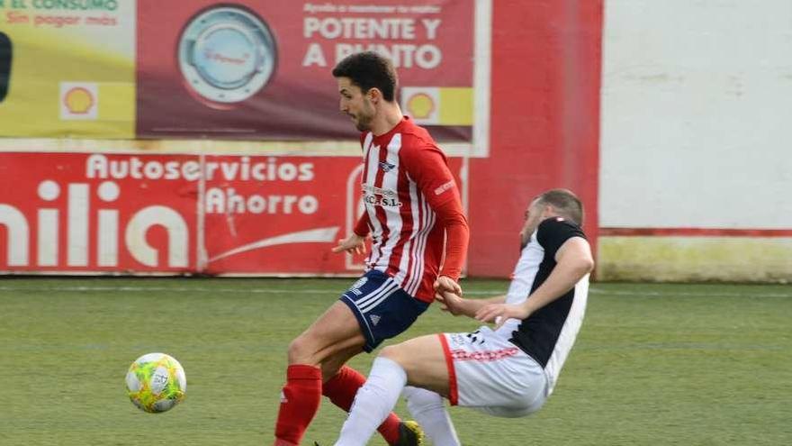 Jonás recibe una entrada de un rival en el partido contra el Estradense. // Gonzalo Núñez