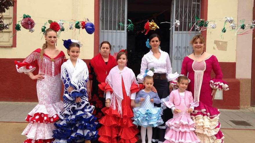Varias vecinas vestidas de flamencas en frente de una peña local.