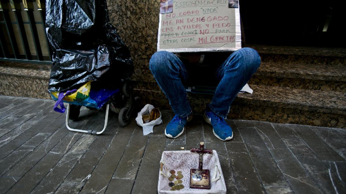 Un mendigo en las calles de Elche con un cartel moviendo a la solidaridad