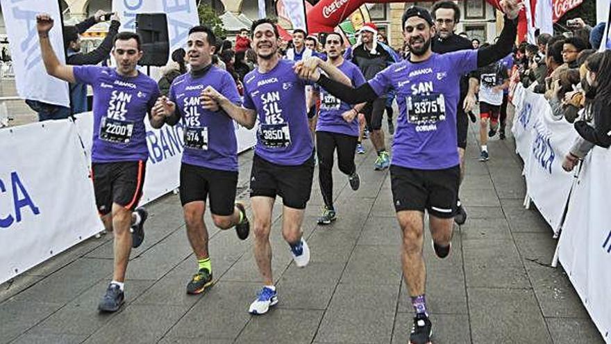 Cuatro corredores, de la mano, llegan a la meta situada en la plaza de María Pita en la pasada edición de la San Silvestre Coruña.