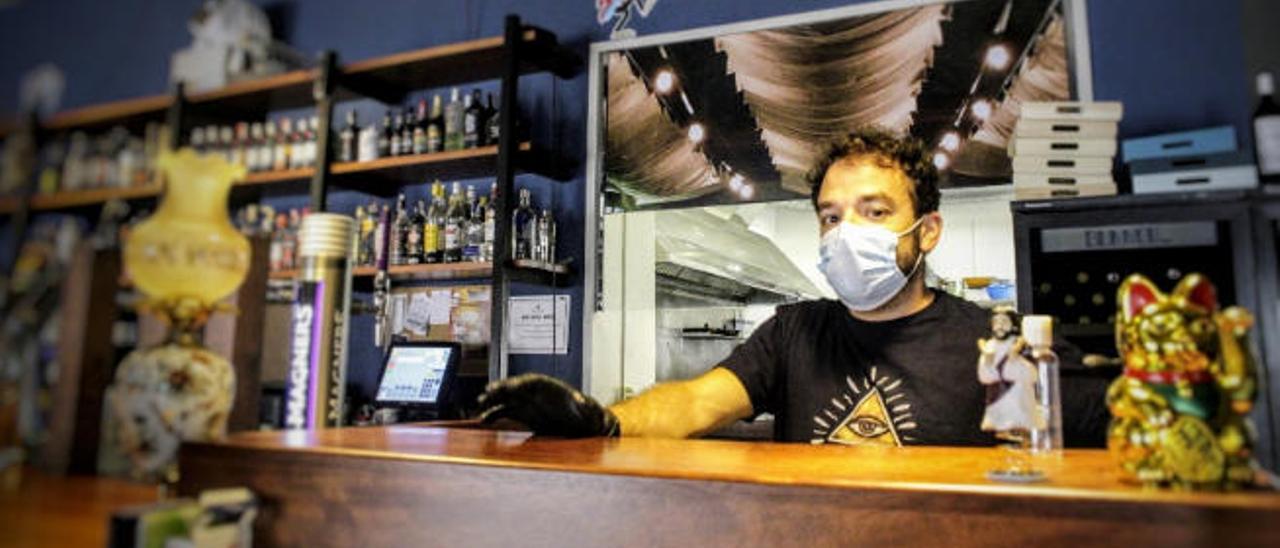 Óscar Rocío, socio del restaurante Dios los cría y el viento los amontona, tras la barra con mascarilla.