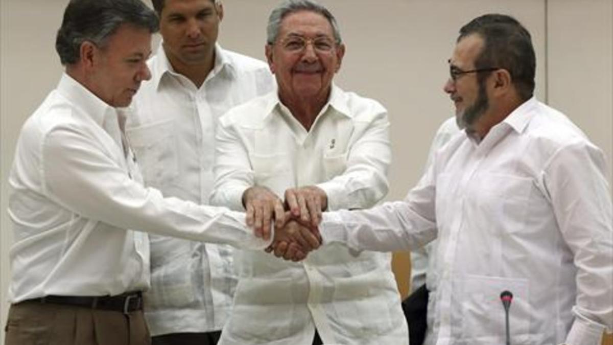 ACUERDO El presidente de Cuba, Raúl Castro, aprieta las manos de Juan Manuel Santos (izquierda) y 'Timochenko', ayer en La Habana.