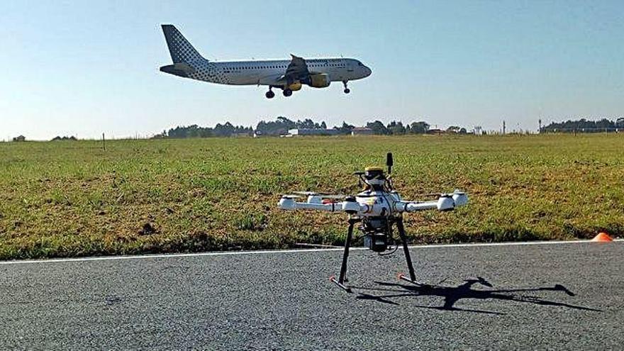 El dron probado ayer por AENA en el aeropuerto de Alvedro, con un avión despegando de la pista al fondo de la imagen.