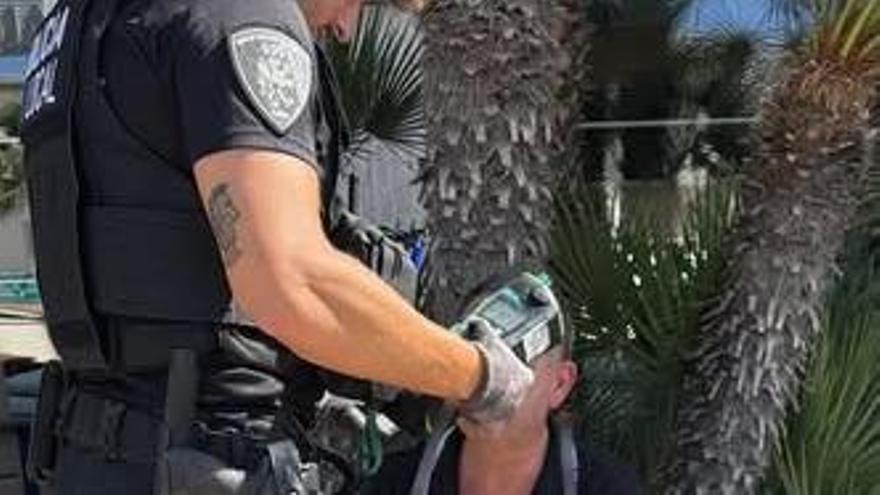 Un policía realiza la prueba de alcoholemia al conductor.