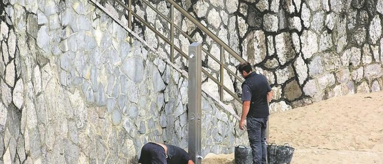 Operarios municipales recogiendo una de las duchas de la playa del Sablón, ayer. Abajo, recogida de ocle, en una imagen de archivo.