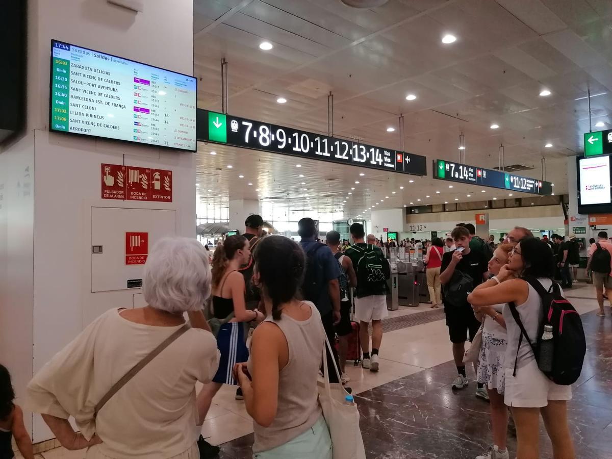 Viajeros de la estación de Sants, en Barcelona, consultan un panel informativo durante la avería que afecta a la circulación de varias líneas de Rodalies y trenes regionales.