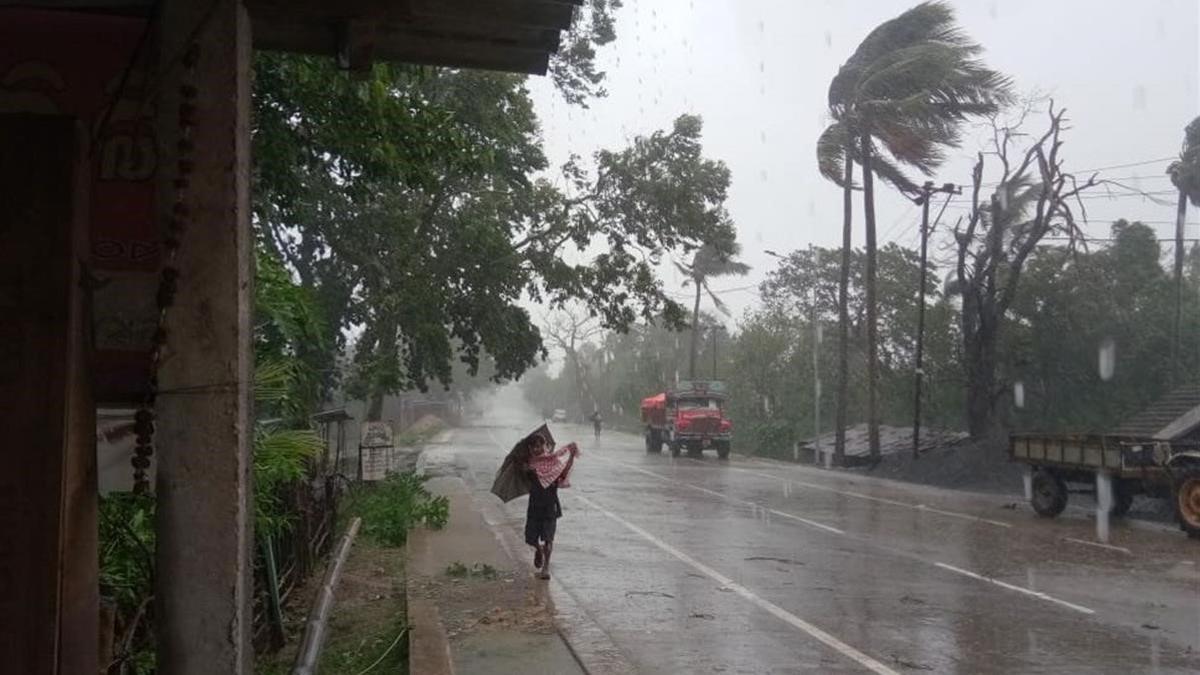 Un hombre se protege de la lluvia y el viento cerca de la localidad india de Dhamra, ante la inminente llegada del ciclón.