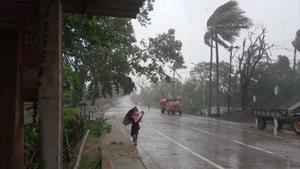 Un hombre se protege de la lluvia y el viento cerca de la localidad india de Dhamra, ante la inminente llegada del ciclón.