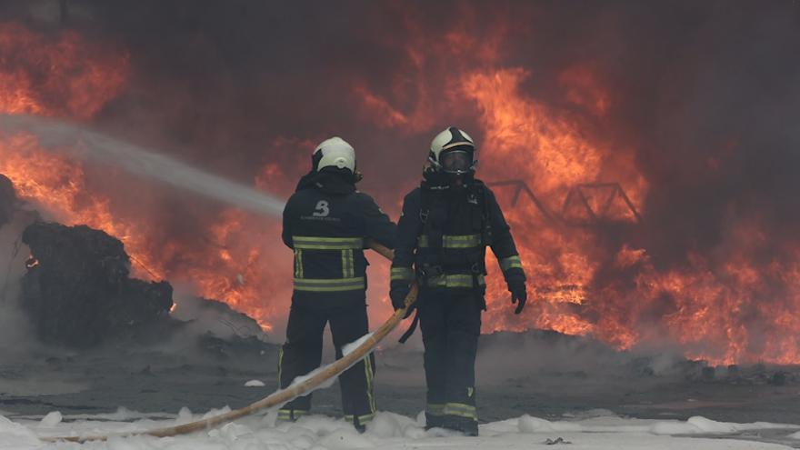 Los bomberos intentando sofocar las llamas en el incendio de Llanera