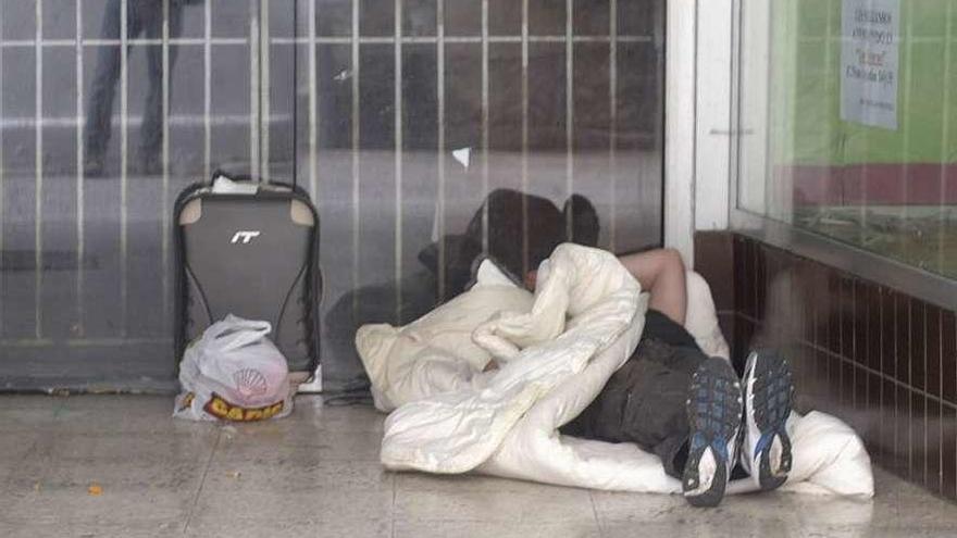 Un hombre duerme en la entrada de un local comercial vacío.