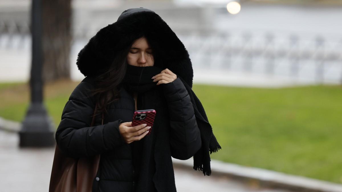 Una mujer consulta su móvil bien abrigada por el frío que está haciendo estos días en Galicia