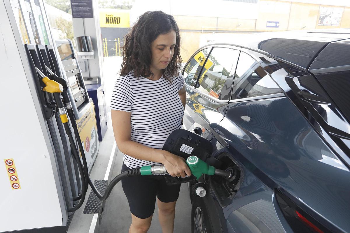 Una dona omplint el dipòsit del cotxe a Girona.