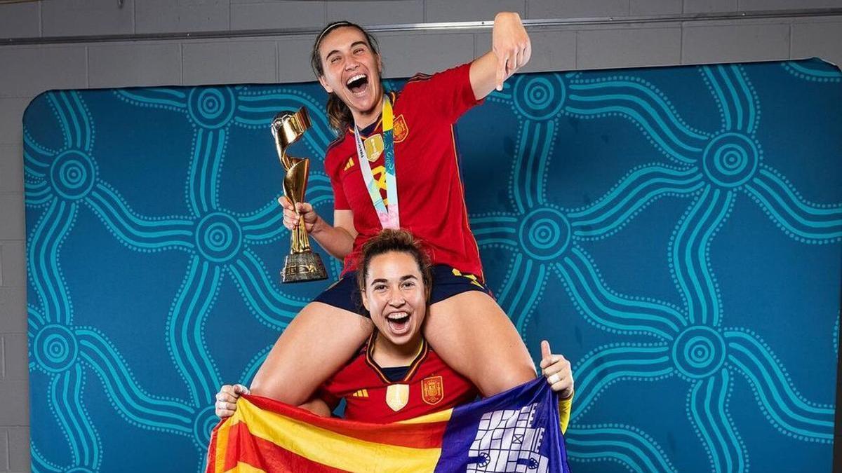Cata Coll y Mariona Caldentey, con la bandera de Mallorca y la Copa del mundo