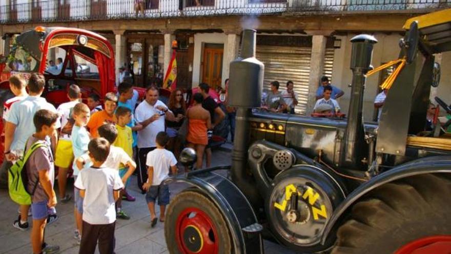 Muchos niños se acercaron a la Plaza Mayor para contemplar los tractores antiguos. A la derecha, el alcalde entrega garbanzos al representante de la Asociación de Amigos de la Maquinaria Agrícola.