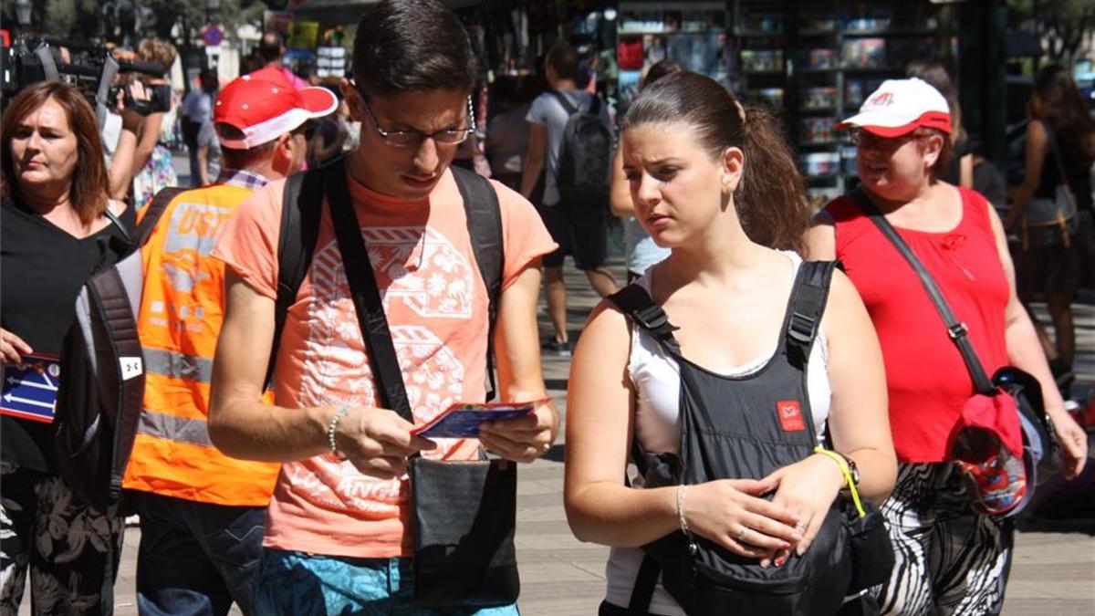 Dos turistas leen la información repartida por UGT en Barcelona sobre explotación laboral de trabajadores de la hostelería.