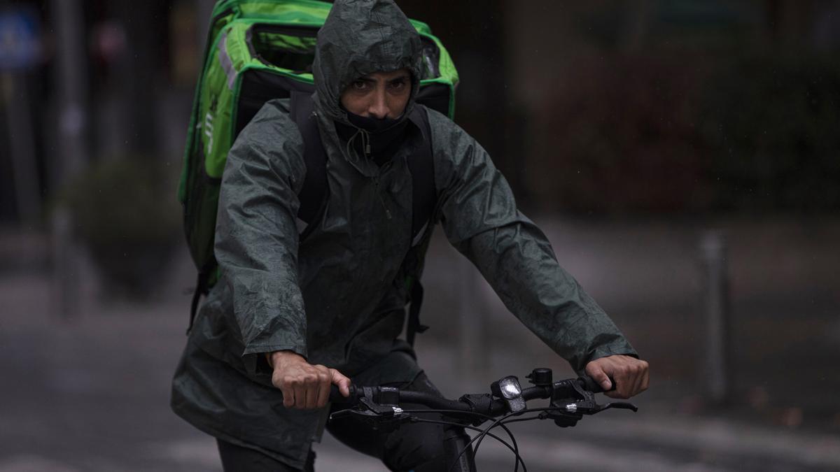 Un rider (repartidor) trabaja bajo la lluvia protegido con un impermeable en una imagen de archivo.