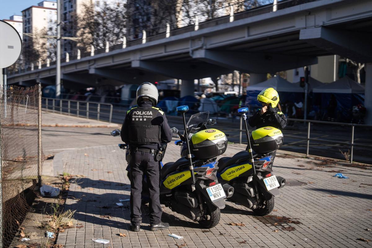 Dos agentes de la Guàrdia Urbana de Badalona frente al asentamineto de los desalojados del B9 bajo la autopista C-31, a finales de año
