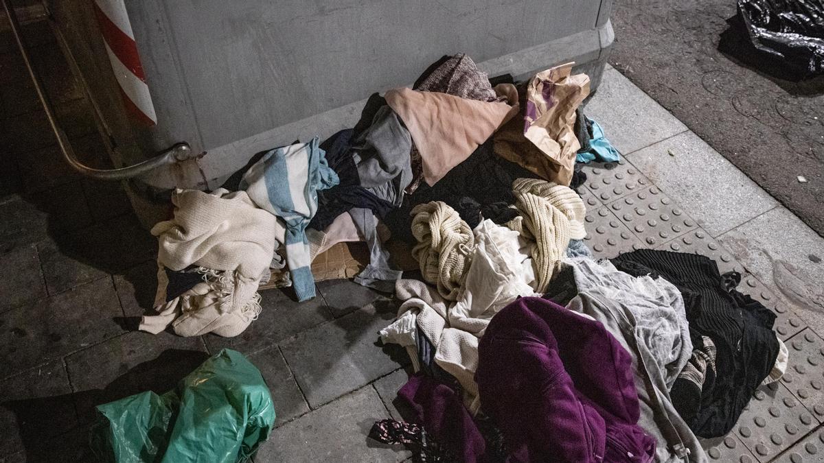 Ropa almacenada junto a un contenedor, en una calle adyacente a la plaza de Trinitat Vella