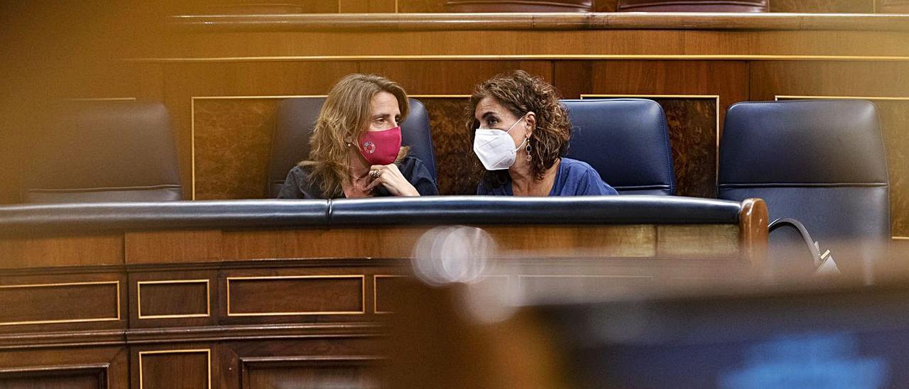 La ministra Teresa Ribera charla con la responsable de Hacienda, María Jesús Montero, en el pleno del Congreso, ayer. | |