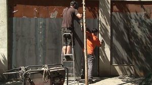 Operaris reforcen el local del ’banc expropiat’ amb més planxes metàl·liques.