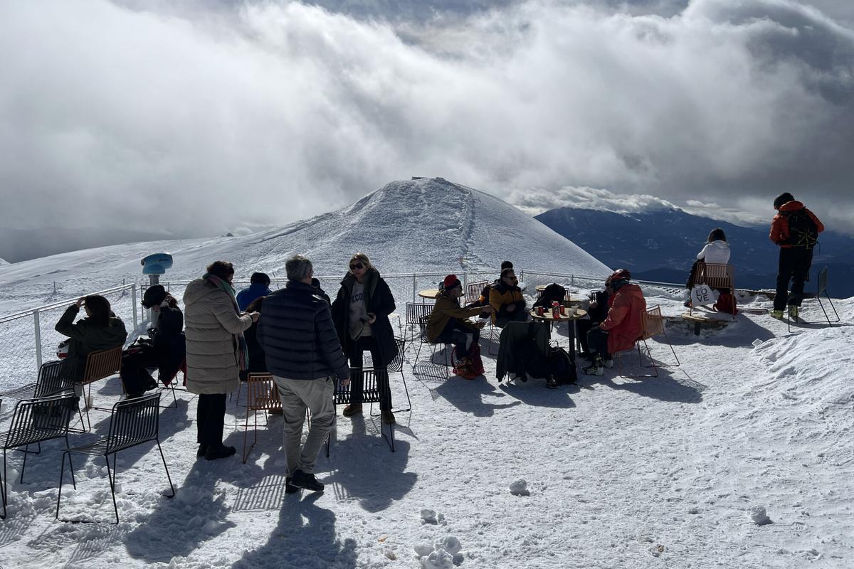 Esquiadors a la terrassa del refugi del Niu de l'Àliga, a l'estació de La Molina (Cerdanya) amb un paisatge totalment blanc al fons