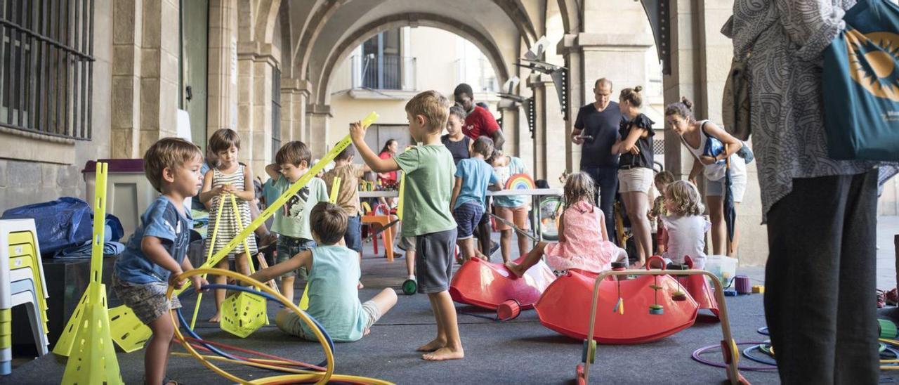 Infants jugant al porxo de la plaça Major, on es van traslladar els jocs per la pluja | OSCAR BAYONA