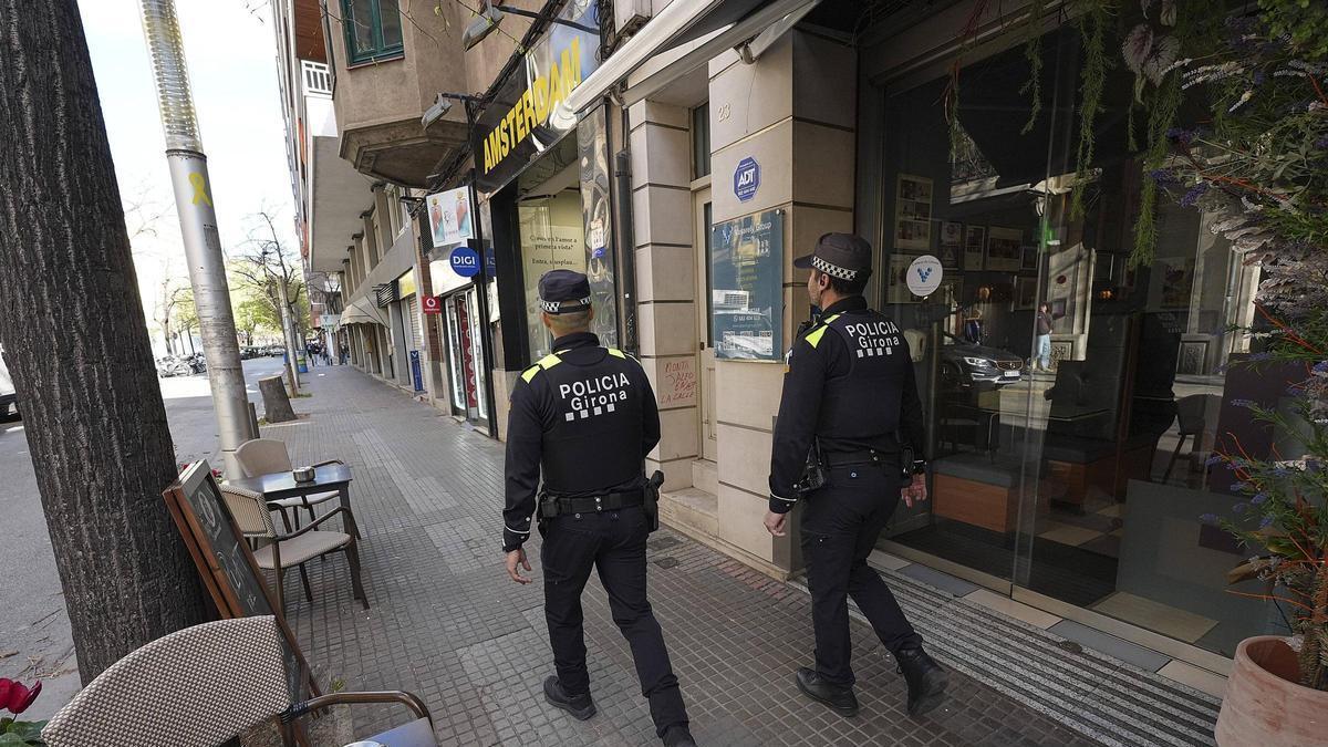 Dos agents de la Policia Municipal patrullant per un carrer de Girona, aquest divendres.