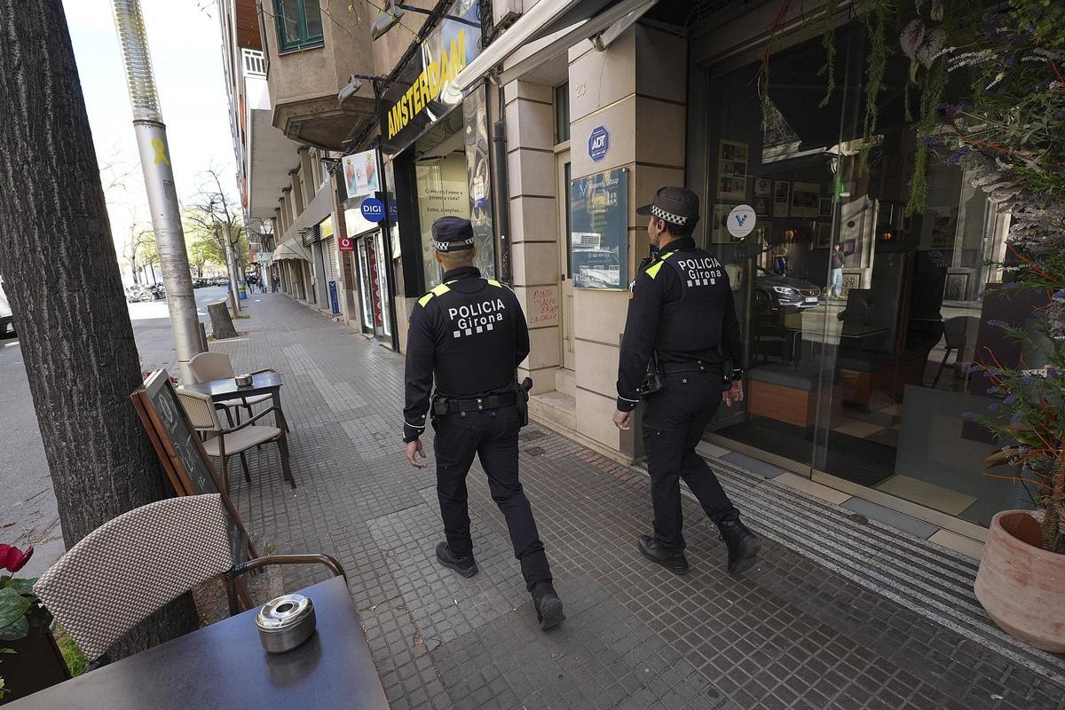 Dos agents de la Policia Municipal patrullant per un carrer de Girona, aquest divendres.