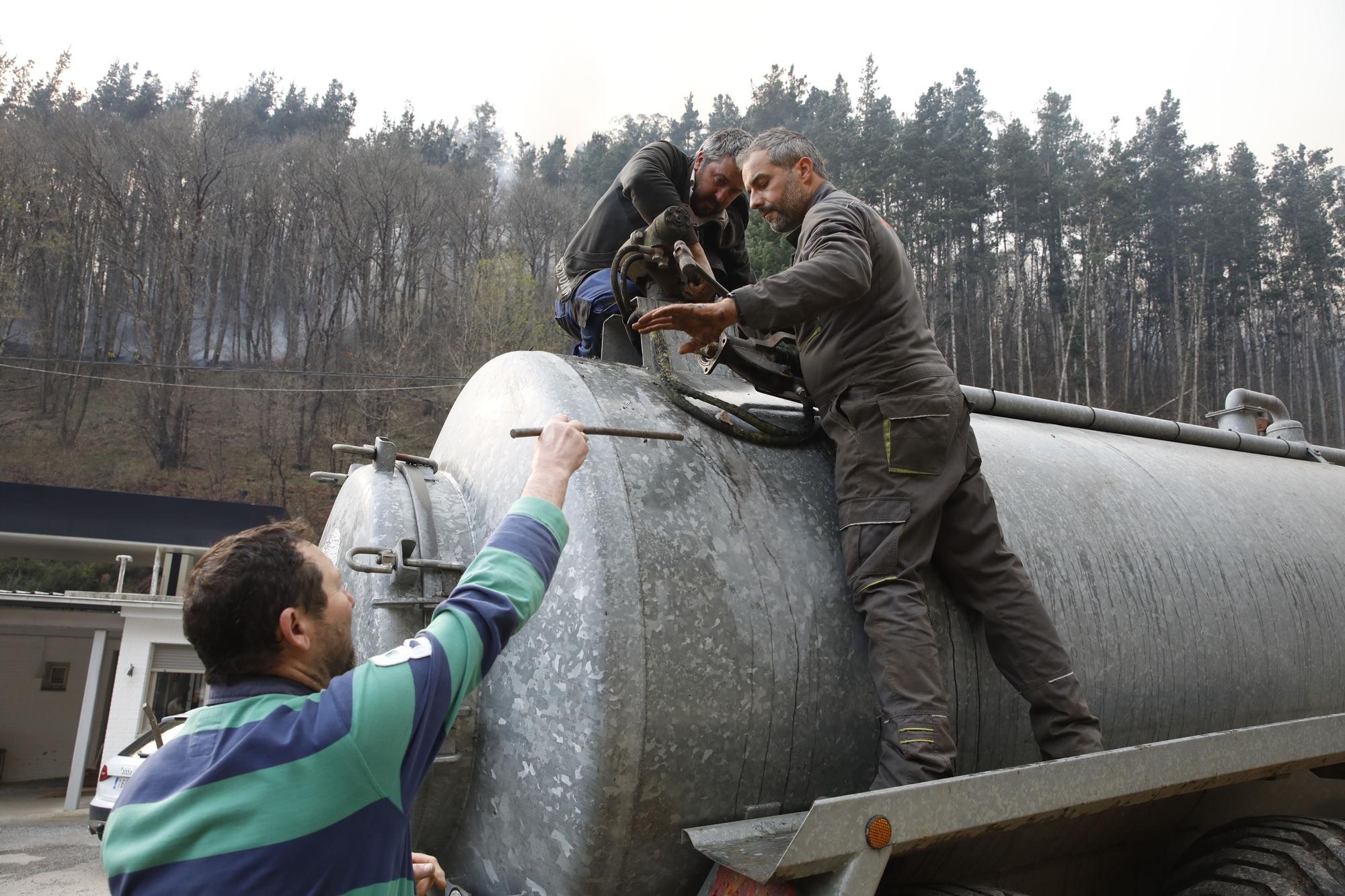 Agricultores ayudando en la extinción de los focos de fuego y enfriando las inmediaciones de la gasolinera de Navelgas
