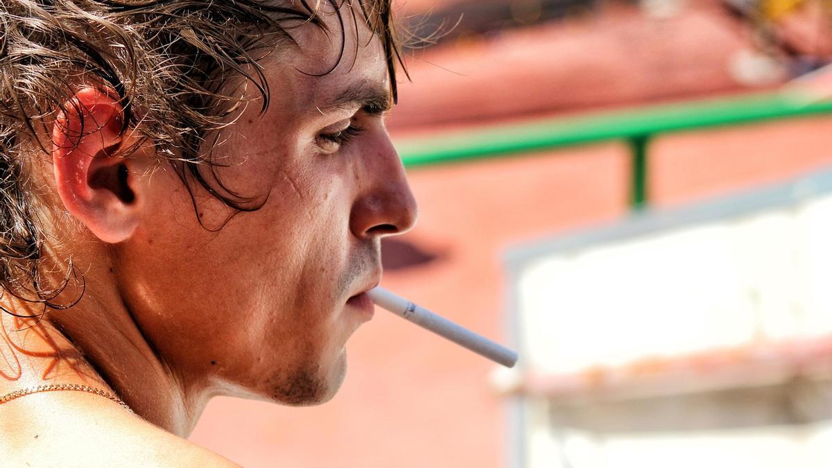 Un hombre fumando en su terraza, algo que se va a acabar