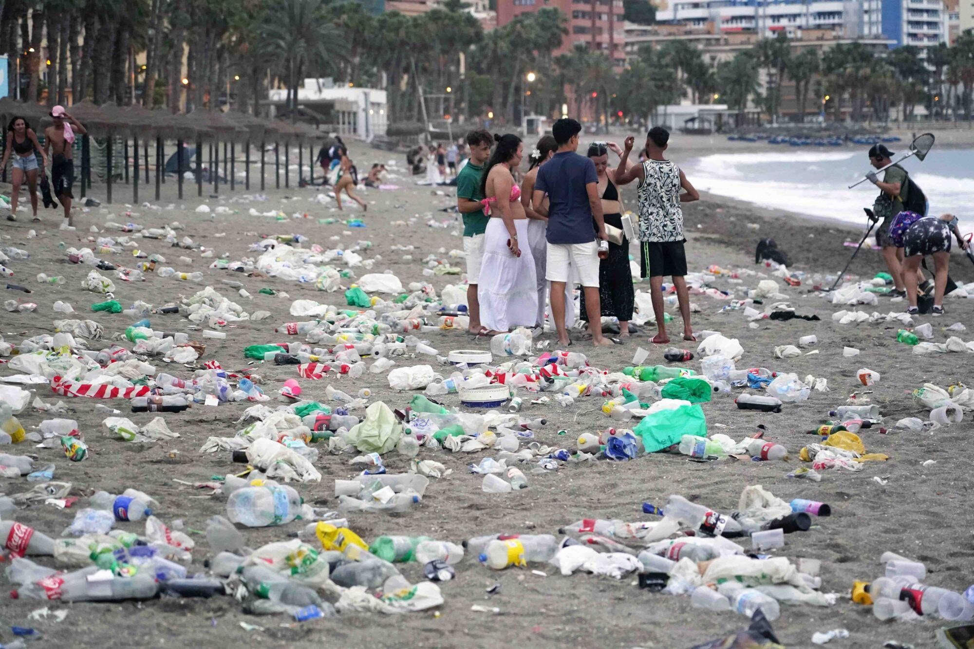 Varios operarios de la empresa de limpieza de Limasam, recogen los residuos de la playa de La Malagueta, tras la Noche de San Juan en Málaga 2025