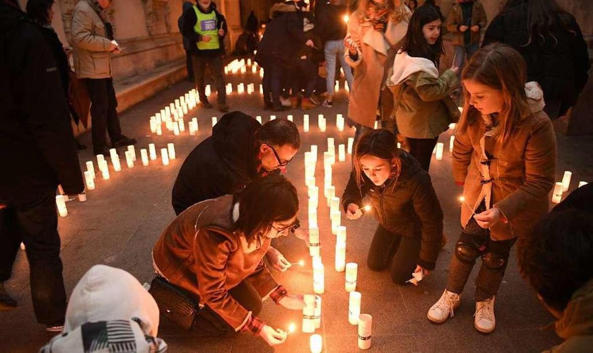 Un grupo de niños enciende velas en los soportales del Palacio Municipal de A Coruña.