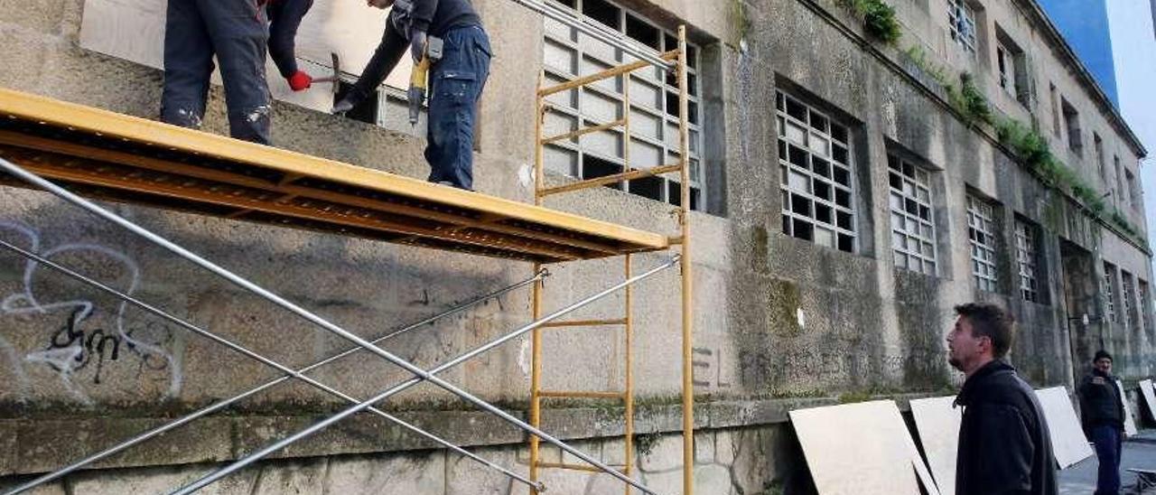 Operarios tapian una nave en ruinas frente al Auditorio de Vigo para evitar la entrada de ocupas. // M.G.B.