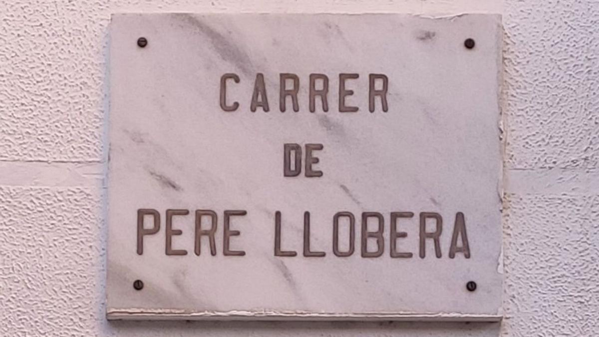 Rótulo de mármol veteado con el nombre de la calle Pere Llorbera en negro.