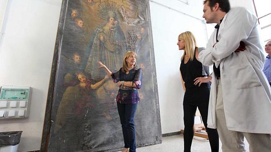 La consellera de Cultura, Trini Miró, contempla en los talleres de Bétera el lienzo de la Virgen hallado en la iglesia de la Mare de Déu de Alcoy.