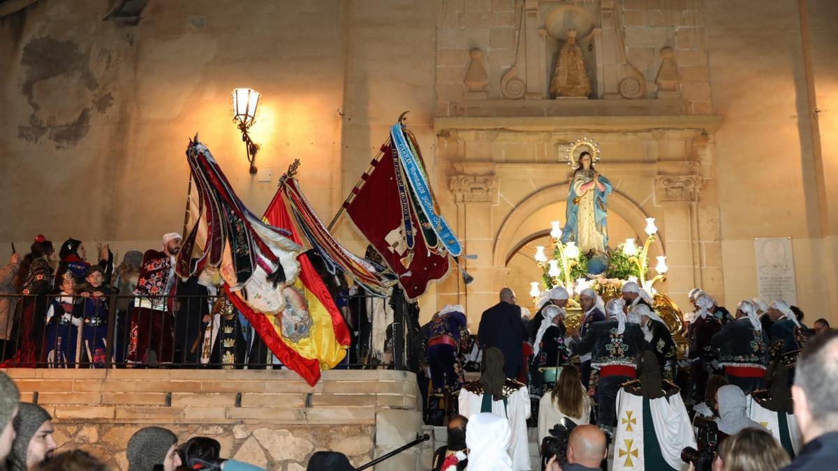 Los Contrabandistas con la patrona de Monforte del Cid en la puerta de la iglesia y con las banderas ondeando.