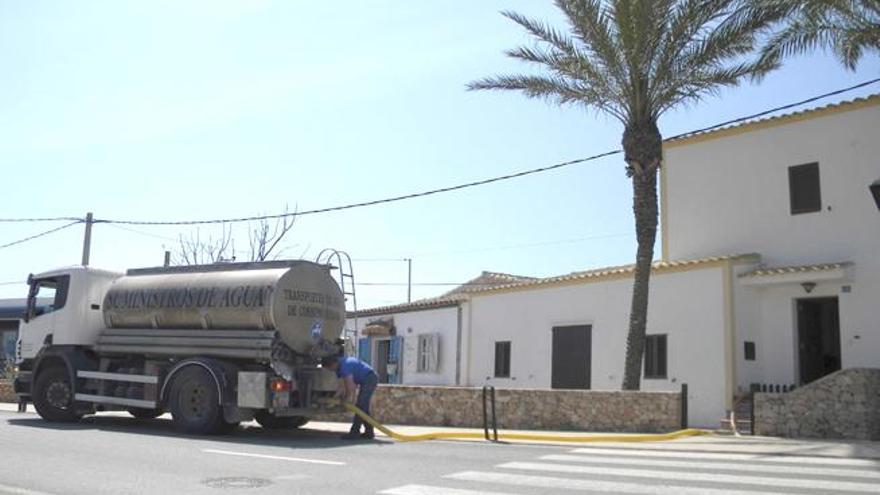 Un trabajador engancha una manguera a un camión cuba para llevar agua hasta una vivienda de la Mola, en Formentera.