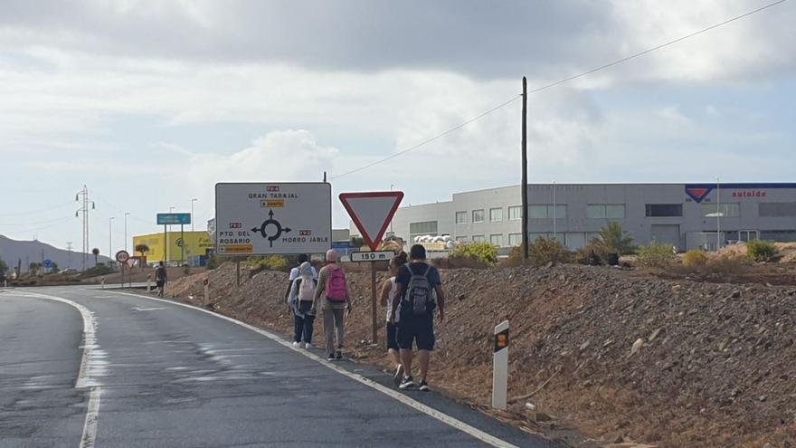 Un grupo de personas se dirige a sus puestos de trabajo caminando junto a la carretera en El Cuchillete.
