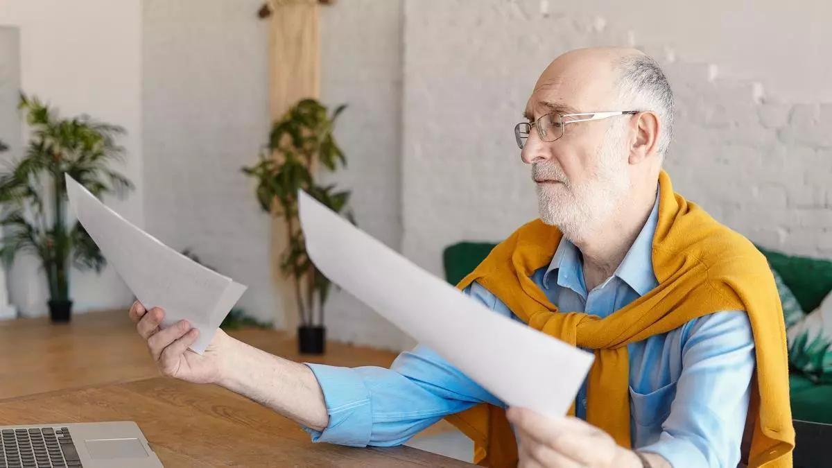 Jubilado observa documento.