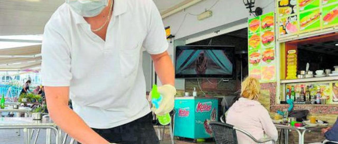 Un camarero desinfecta la mesa de una terraza en Arguineguín.